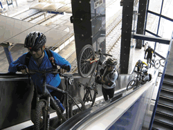 ciclista a andarem com a bicicleta nas escadas rolantes