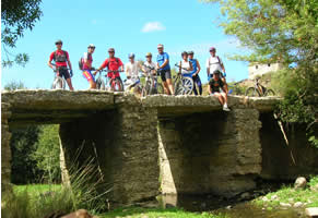 ciclistas em pose sobre ponte antiga no vale da cabrela